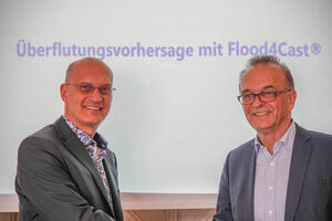 Bürgermeister Karl Dieter Wünstel und Landrat Dr. Fritz Brechtel geben sich die Hand. im Hintergrund eine Powerpointpräsentation mit der Überschrift Flutungsvorhersage mit Flood4Cast
